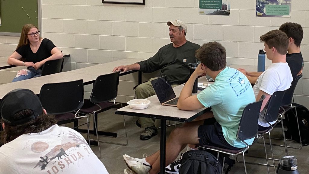 Author Jeff Nania sits with students in a class discussion.